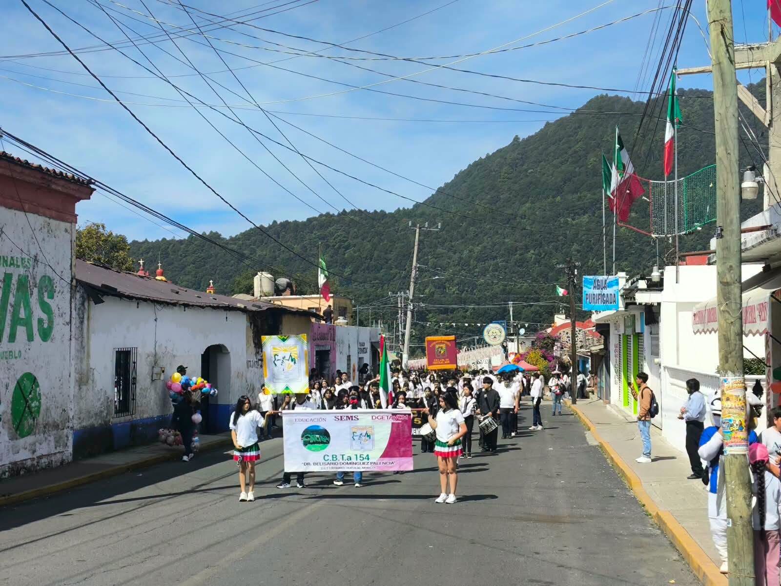 Estudiantes desfilando por las calles de Huitzilac con el estandarte del plantel